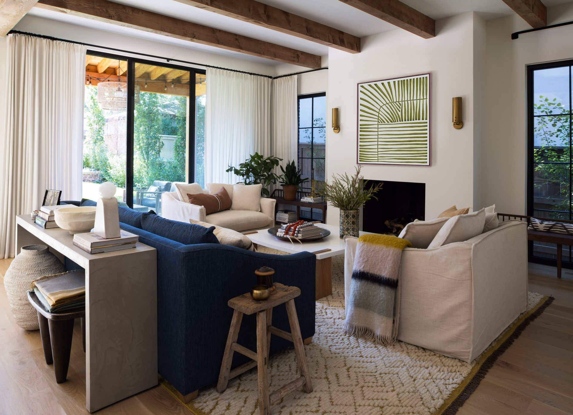 A living room with sliding doors, white drapes, furniture and a fireplace.