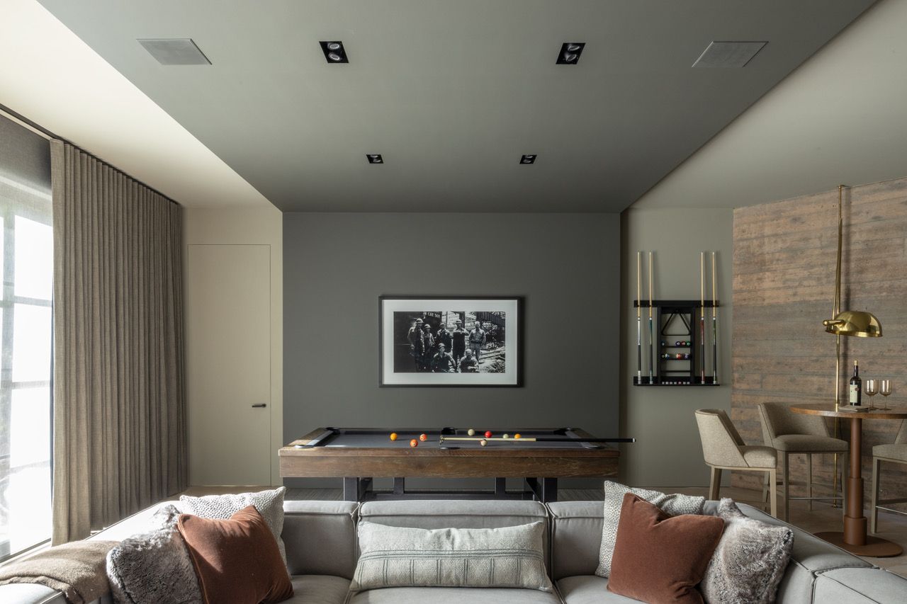 A living room with a pool table and a couch and blackout draopes