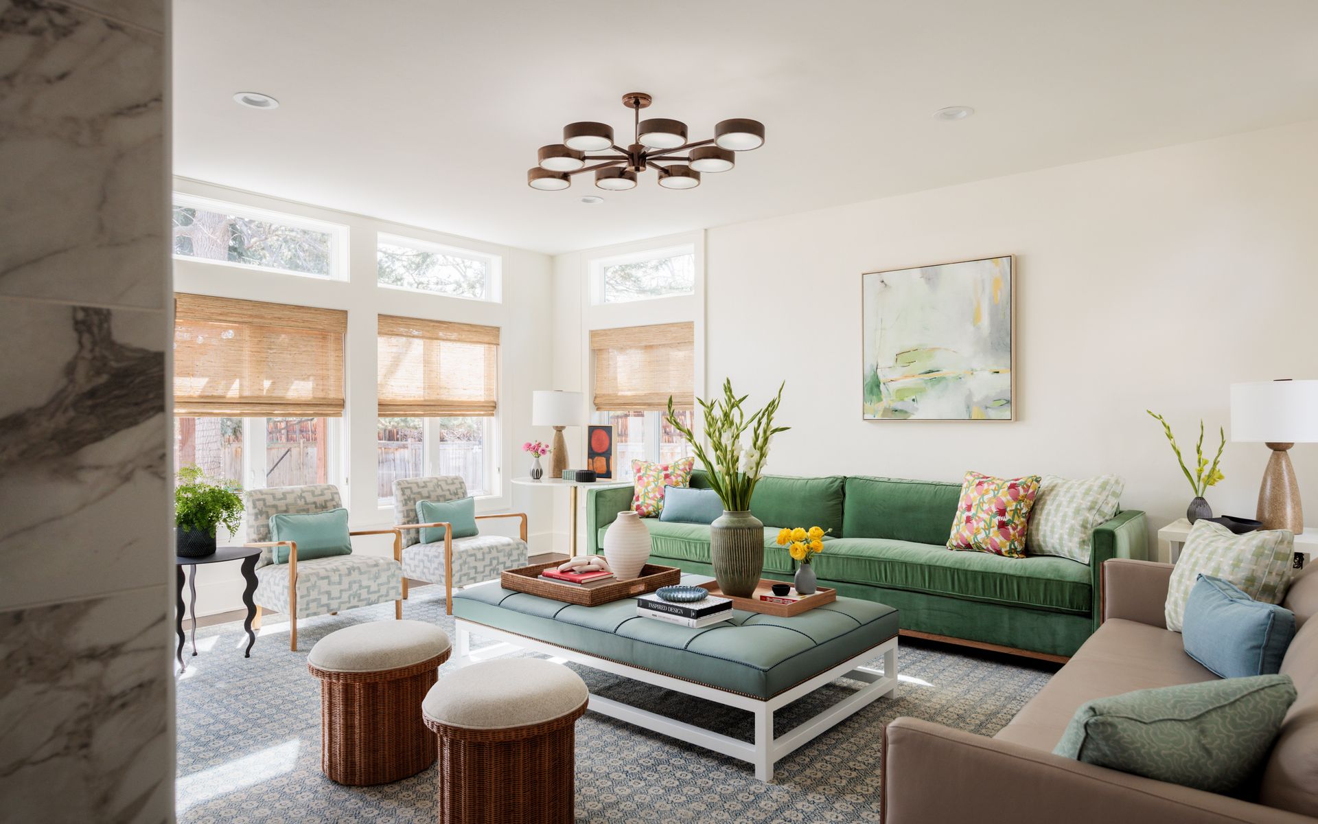 A living room with a green couch and a white coffee table and light bamboo woven shades