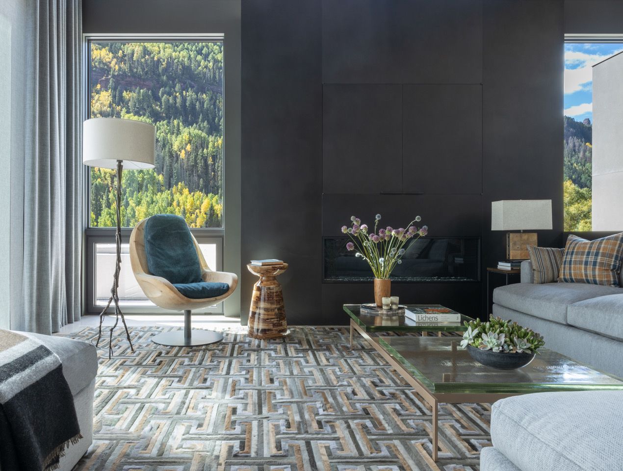 A living room with a motorized drapes couch , chair , coffee table and rug.