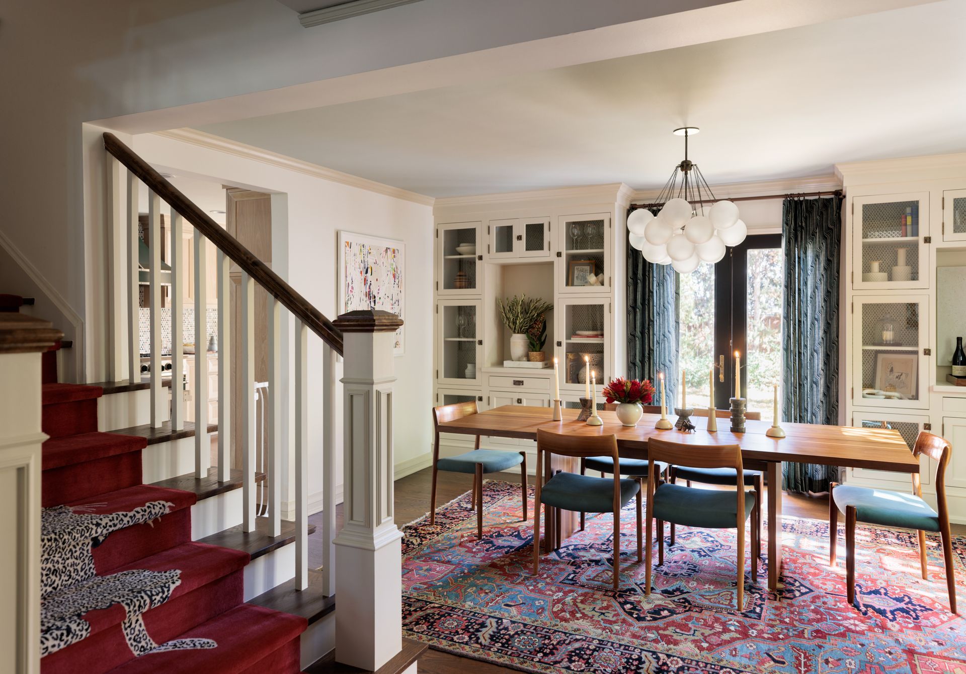 A dining room with a long table and chairs and stairs leading up to it.