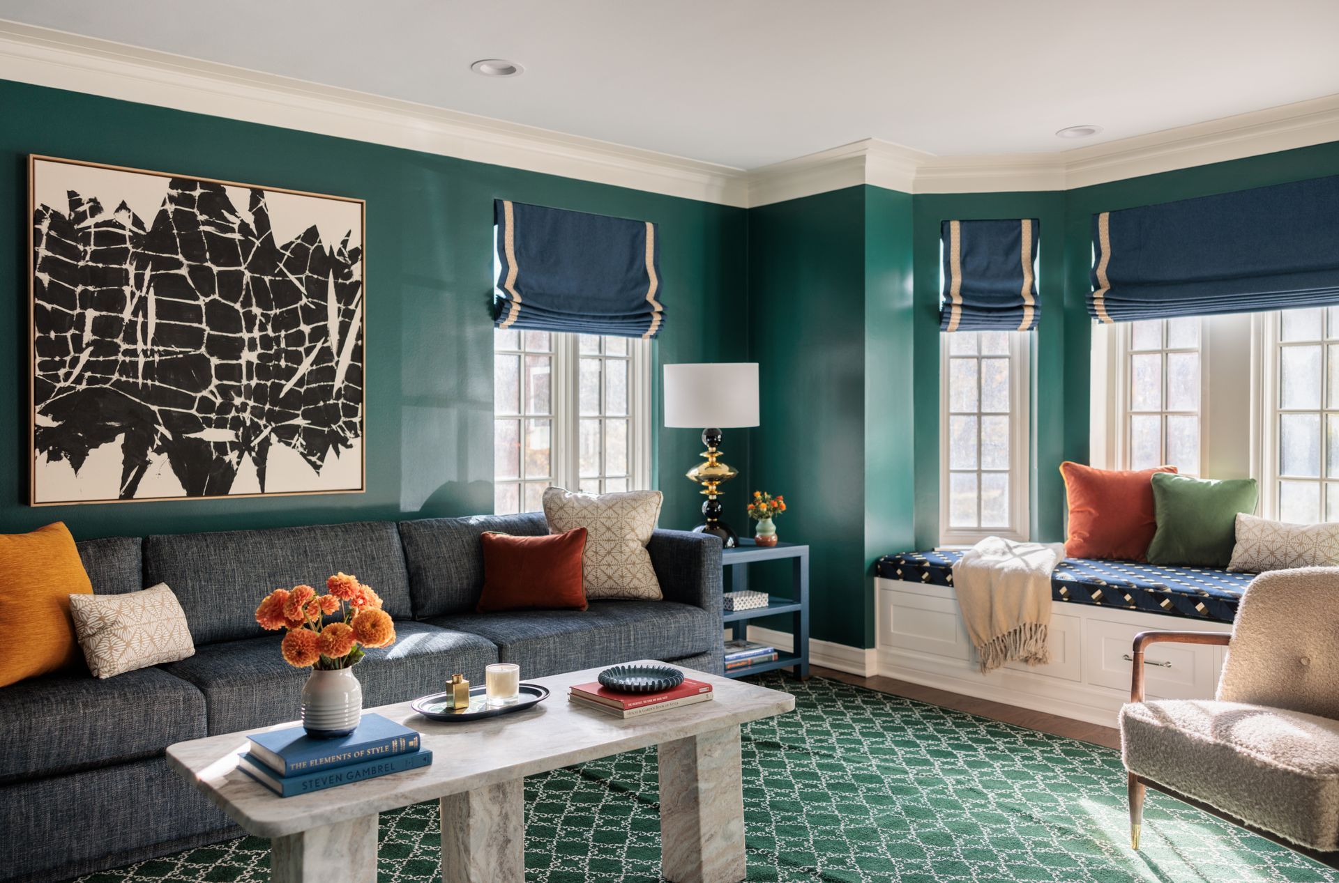 A living room with green walls , a couch , a coffee table , and a window seat.