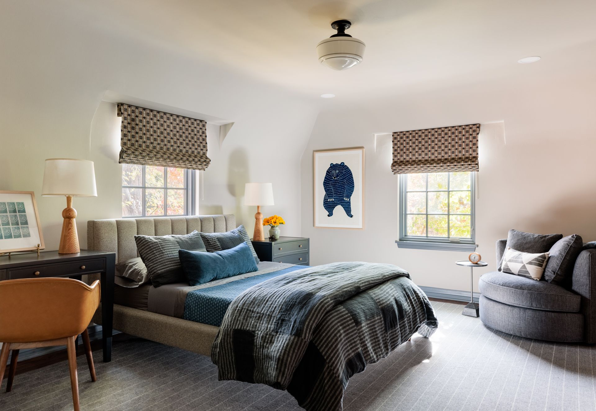 A bedroom with a bed , chair , desk and window.