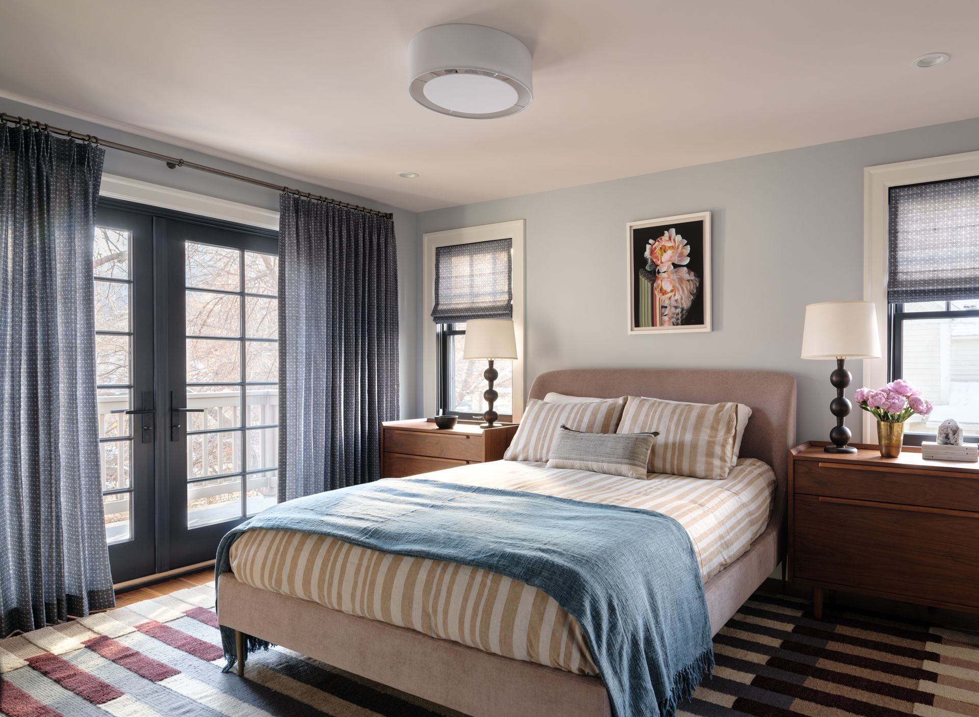 A bedroom with a bed , nightstands , lamps and a rug.