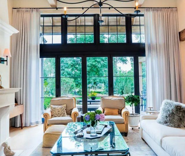 A living room with tall black windows, two-story drapes, and furniture