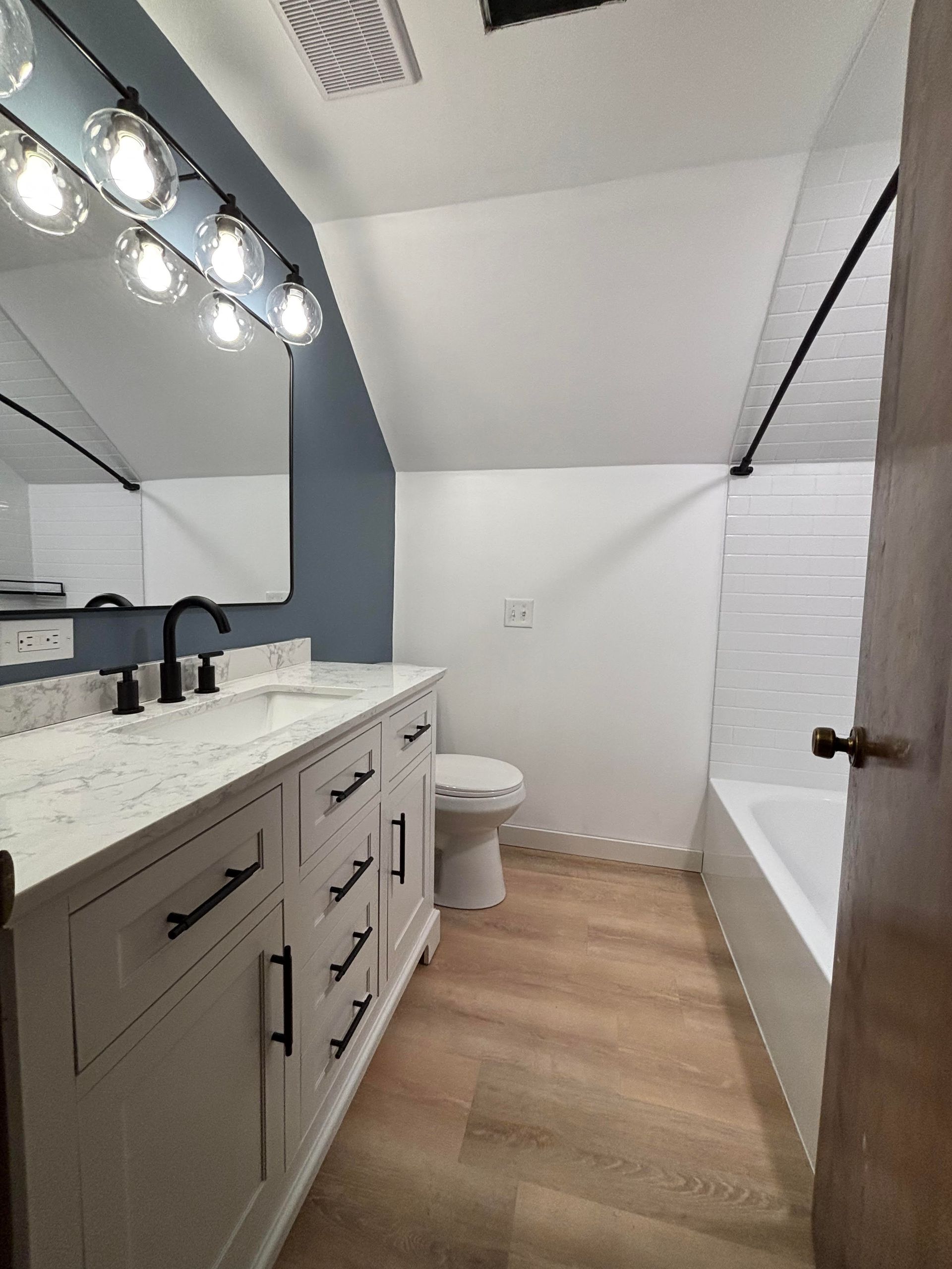 Bathroom with a shower, toilet, and window, featuring light gray flooring and walls, black fixtures.