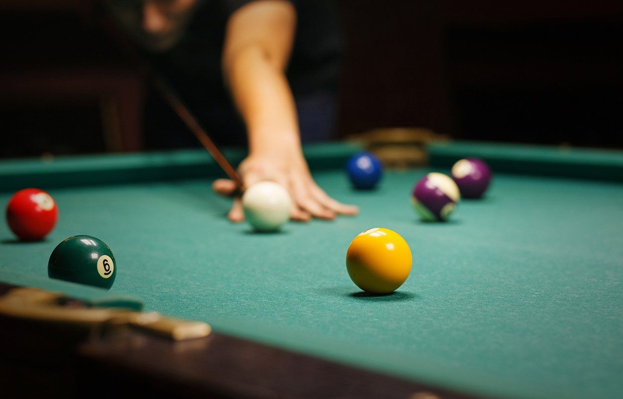 Person about to strike the cue ball on a pool table