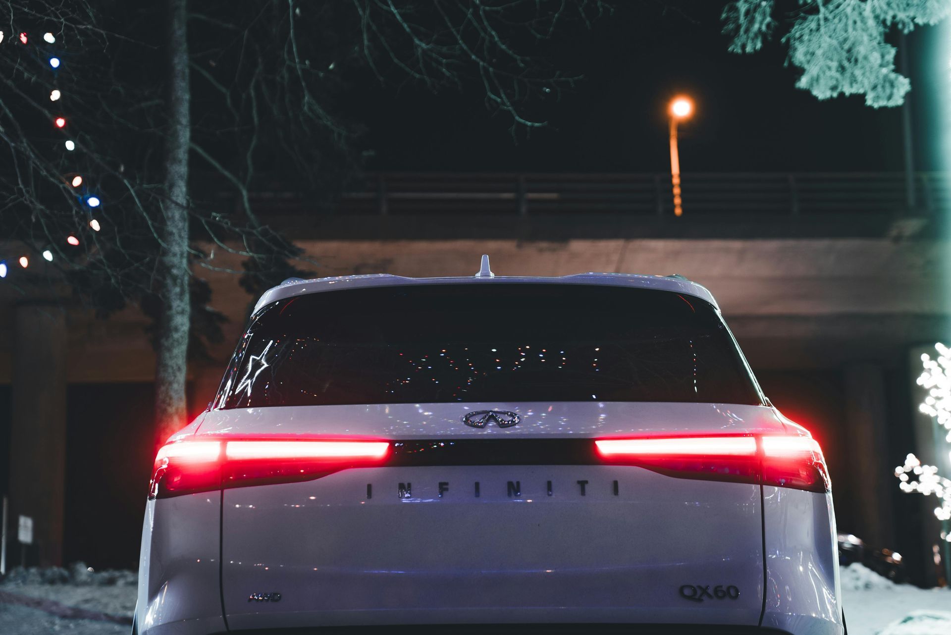 White SUV at night with red taillights on a snowy street