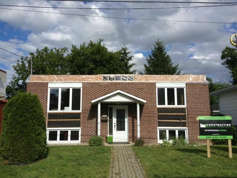 Une maison en briques avec un panneau devant
