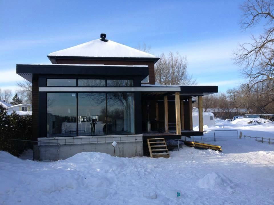 Une maison avec beaucoup de fenêtres est couverte de neige.