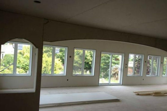 Une grande pièce vide avec beaucoup de fenêtres et de portes coulissantes en verre