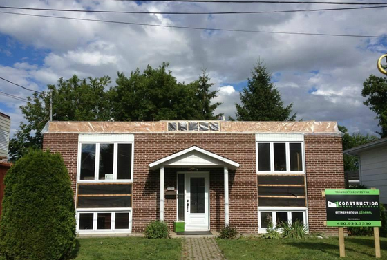 Une petite maison en briques avec un panneau devant