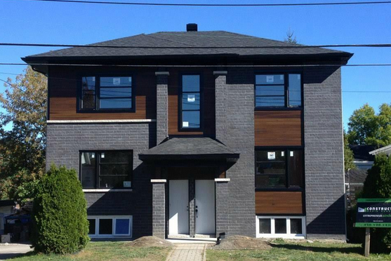 Une grande maison en briques avec beaucoup de fenêtres et un toit noir.