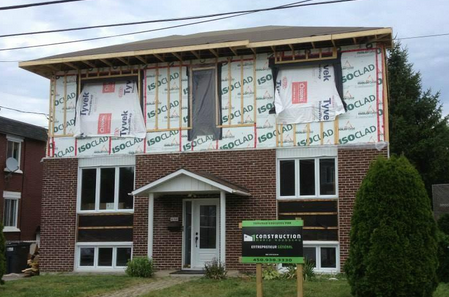 Un bâtiment en briques en construction avec une pancarte devant