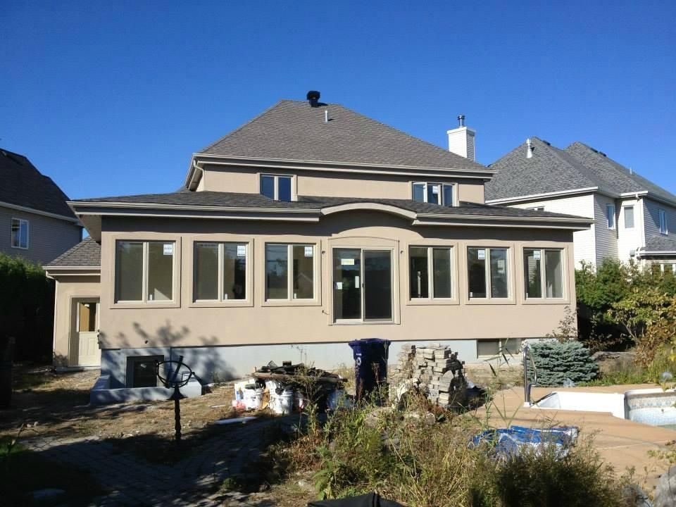Une grande maison avec beaucoup de fenêtres et une piscine dans l'arrière-cour