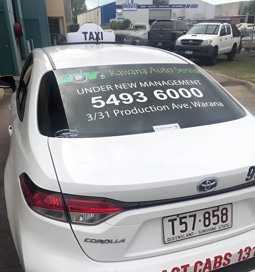 A White Car With a Taxi Sign on Top of It is Parked in Front of a Building — Kawana Auto Service In Warana, QLD