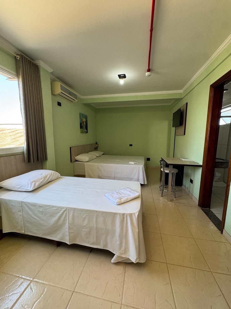 Um quarto de hotel com três camas e uma mesa.