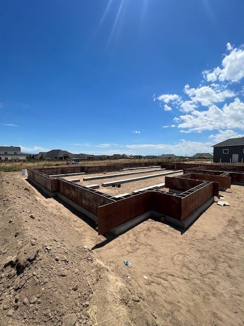 A concrete foundation with wooden forms for a new house under construction on a sunny, clear day.