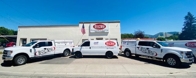 Three white trucks are parked in front of a building.