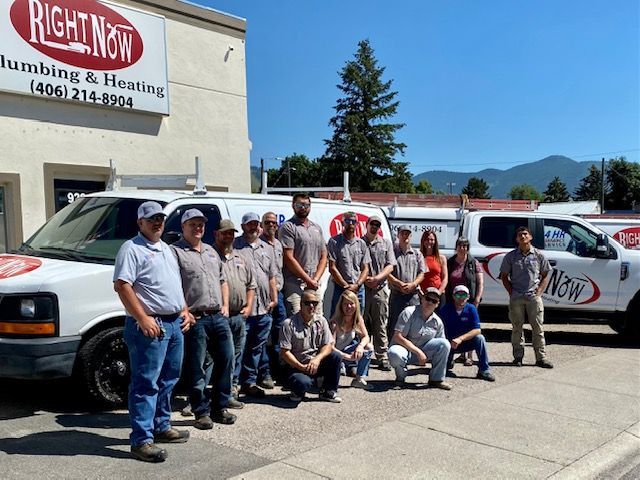 A group of people standing in front of a building that says right now plumbing and heating