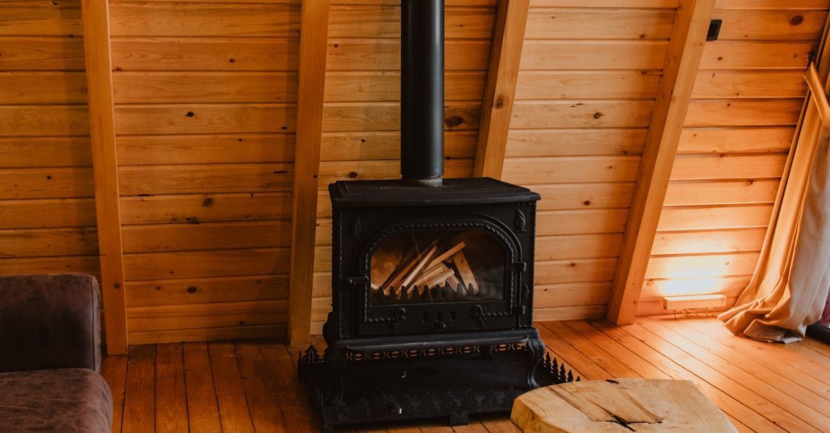 A wood stove is sitting in a wooden room next to a couch.