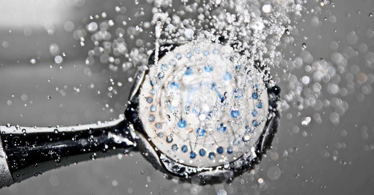 A close up of a shower head with water splashing out of it.