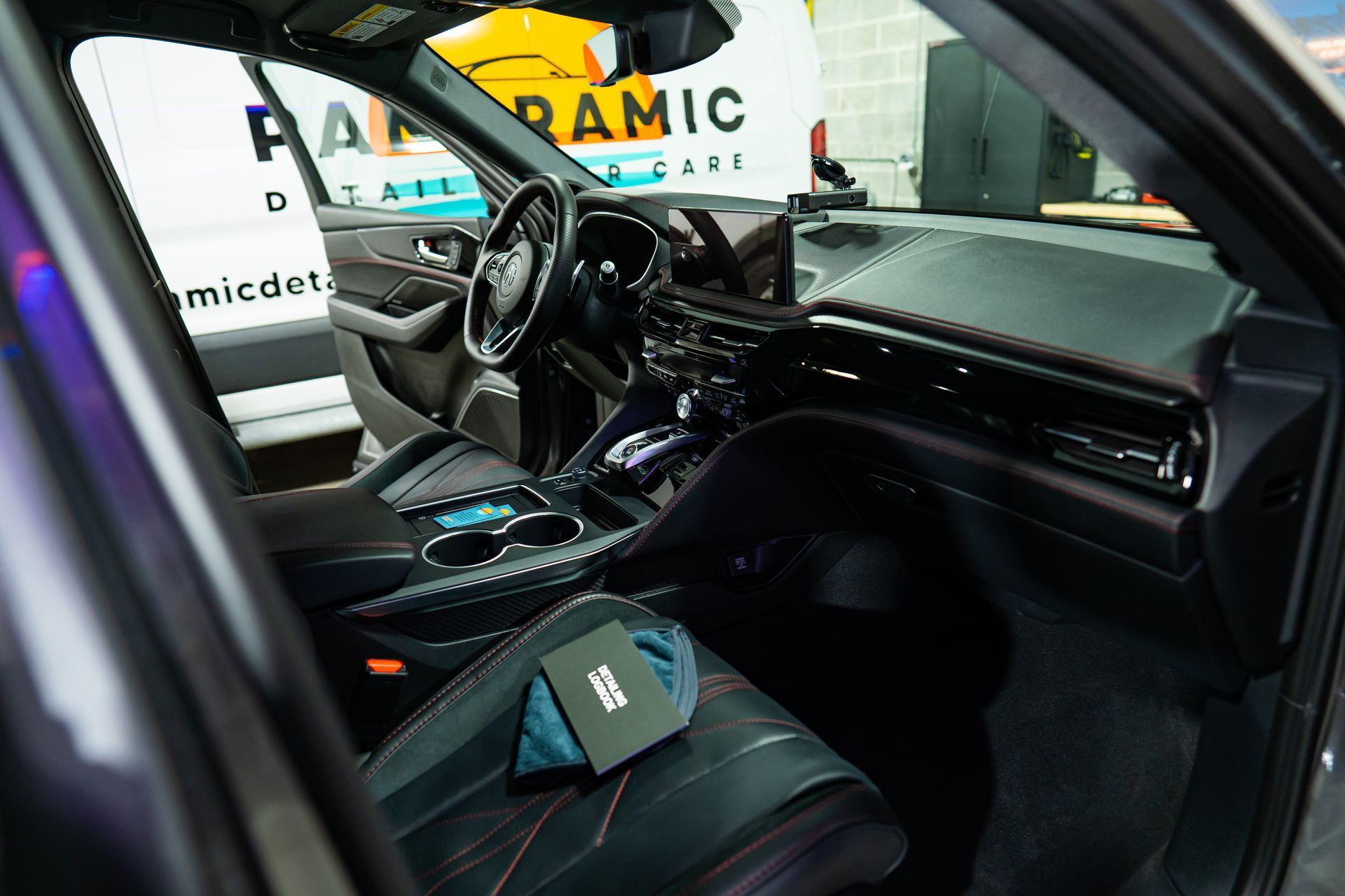 The interior of a modern car, featuring leather seats with red stitching, a digital dashboard, and a sleek console.