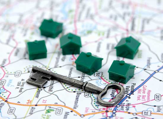 House key on a map with small plastic house pieces