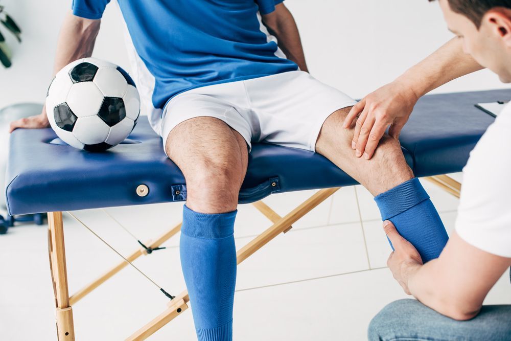 A soccer player is getting his knee examined by a doctor.