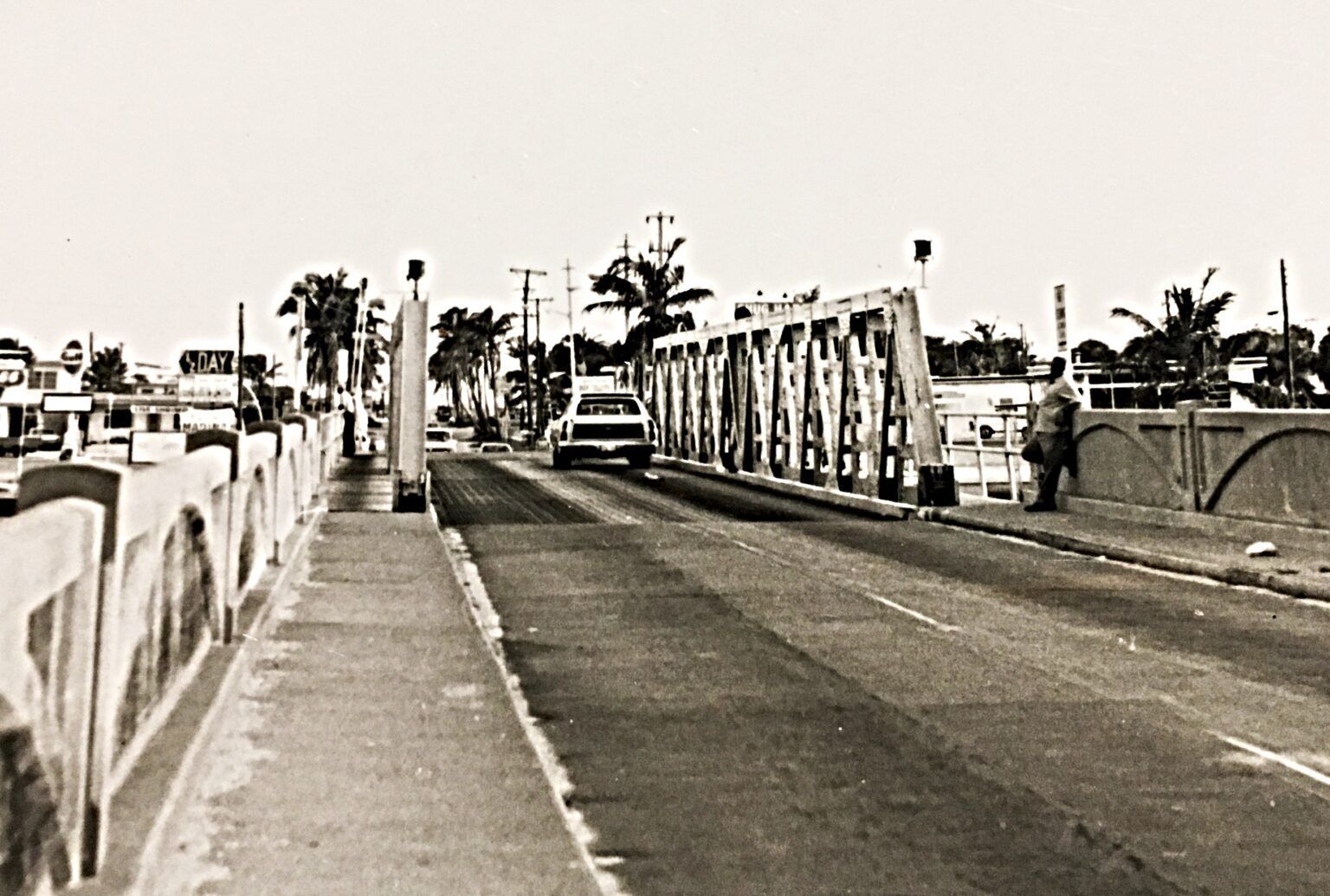 A black and white photo of a bridge over a road.