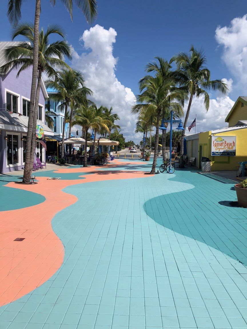 A colorful street with palm trees and buildings on a sunny day