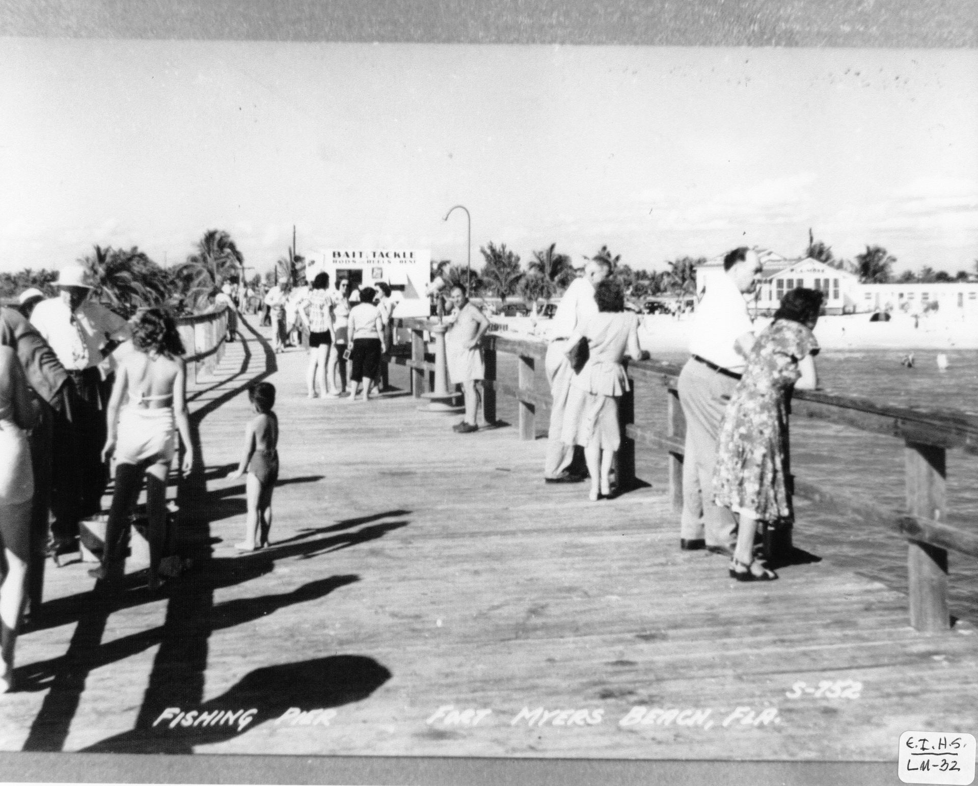 A black and white photo of people standing on a pier