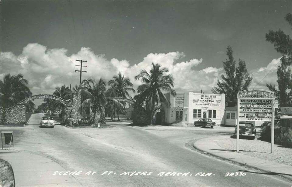 A black and white photo of a street with palm trees