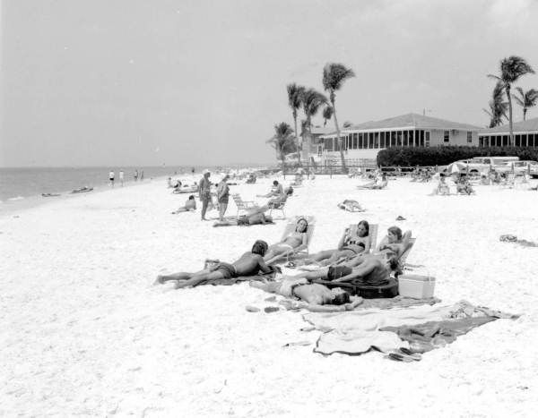 A black and white photo of people laying on the beach