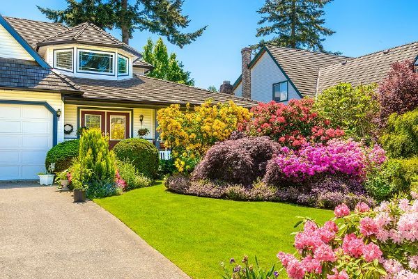 A house with a lush green lawn and flowers in front of it.