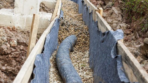 A drain pipe is being installed in a trench.