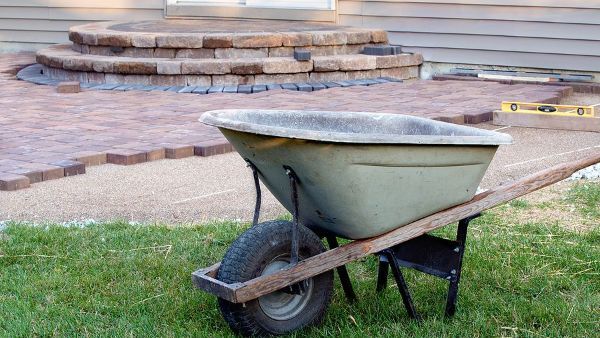 a wheelbarrow is sitting in the grass in front of a house .