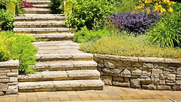 A set of stairs leading up to a stone wall in a garden.