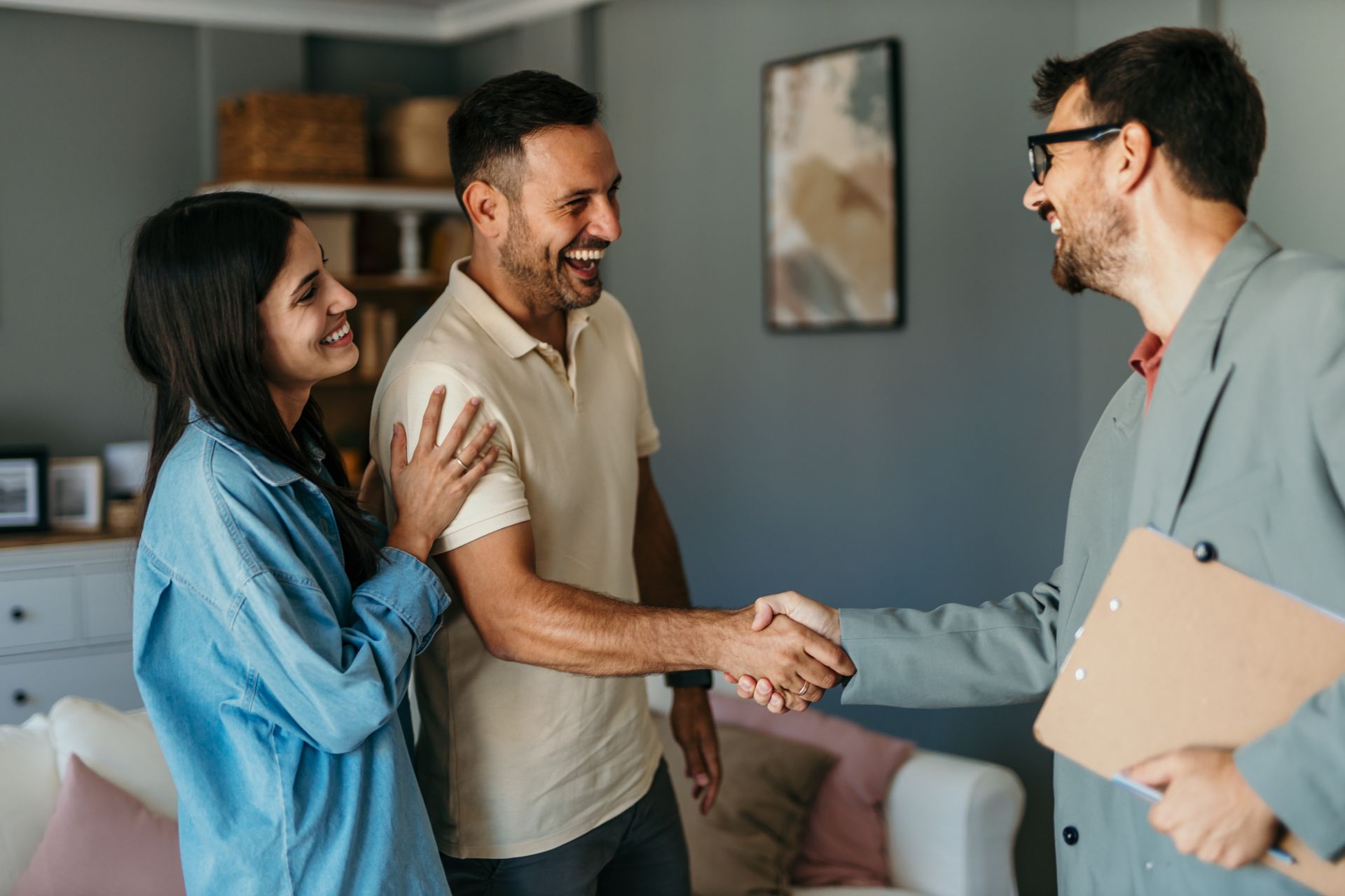 Two men shaking hands in a building under construction. One in a suit, one in a work vest, smiling.