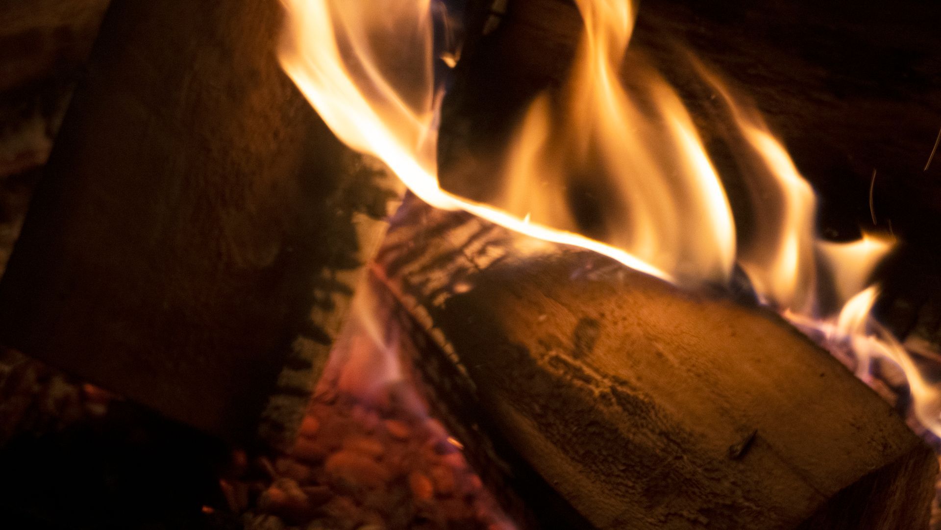 Close-up of burning firewood with orange and yellow flames.