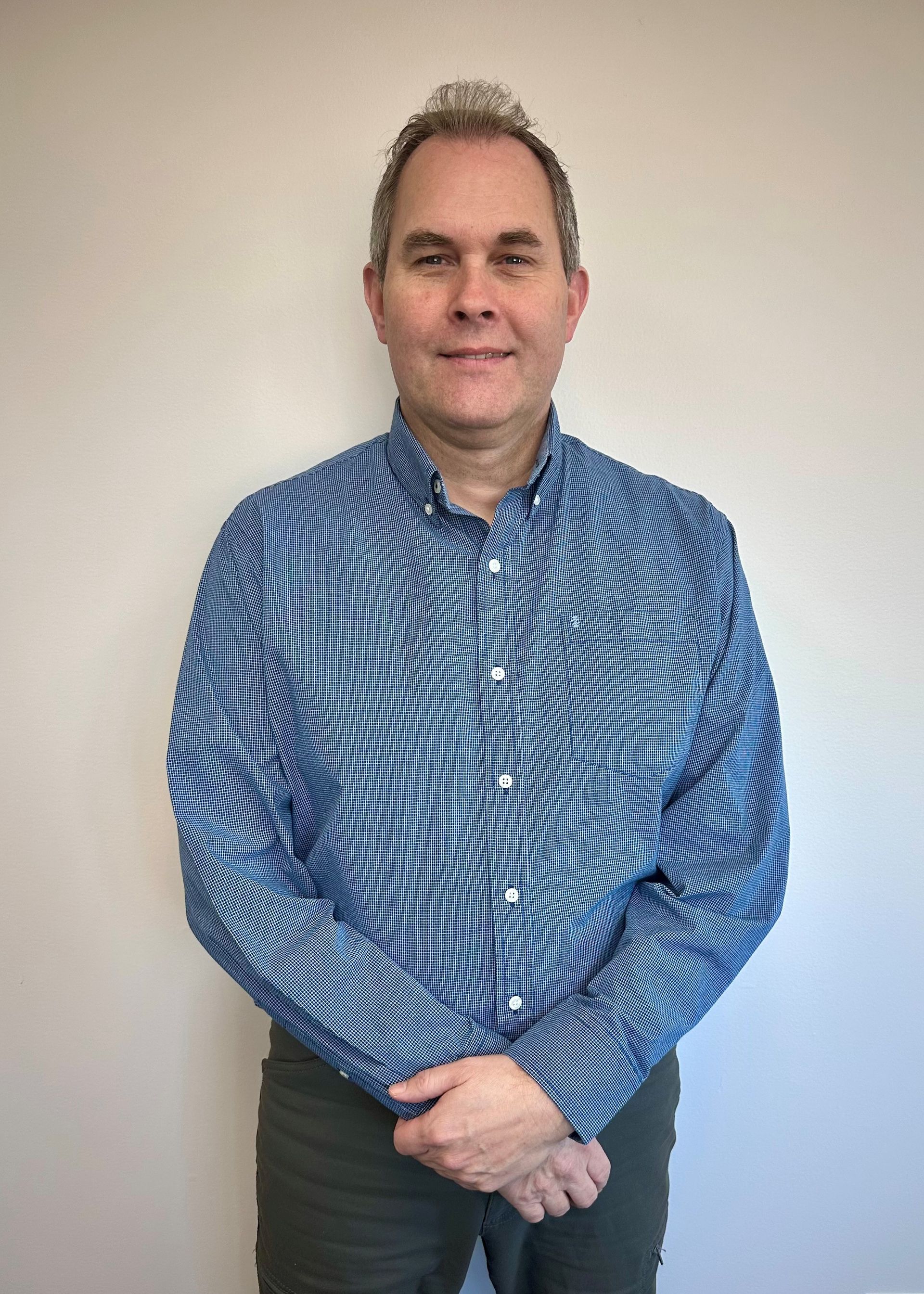 Man with glasses smiling, wearing a blue shirt.