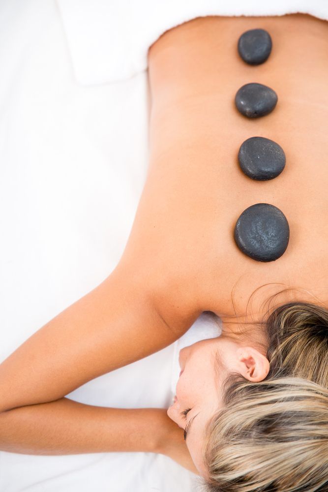 A Woman Is Getting A Hot Stone Massage On Her Back — Ocean Bliss Thai Massage In Ballina, NSW