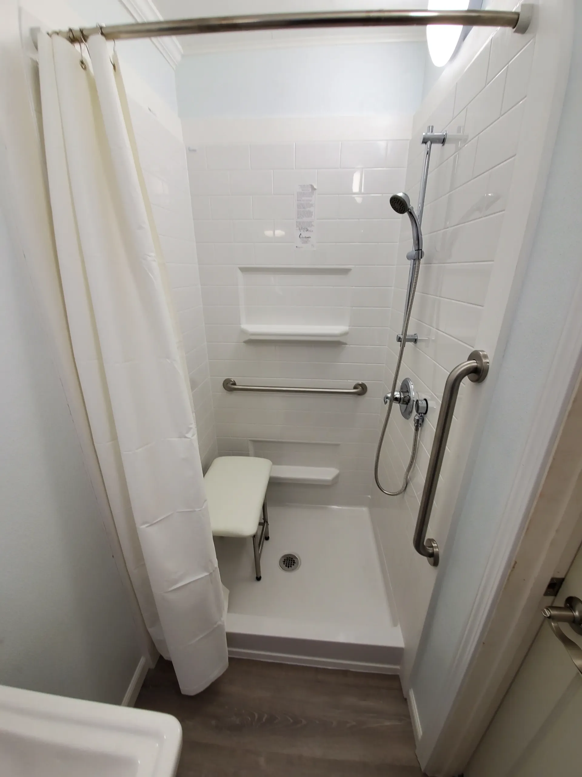 A bathroom after an accessible bathroom modification by Altamira Ltd. with a walk in shower and a sink.