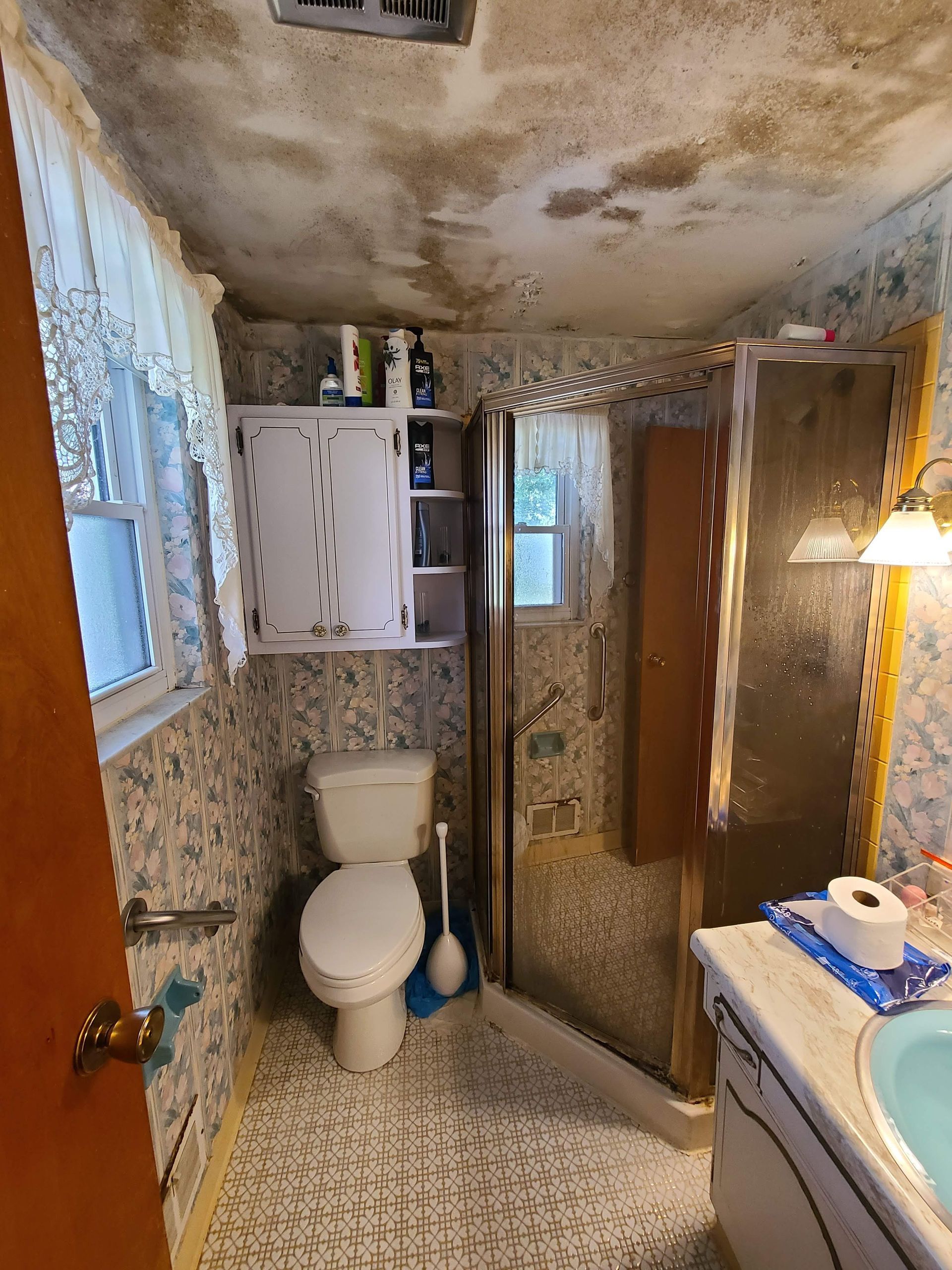 A bathroom with a toilet , sink and mirror.