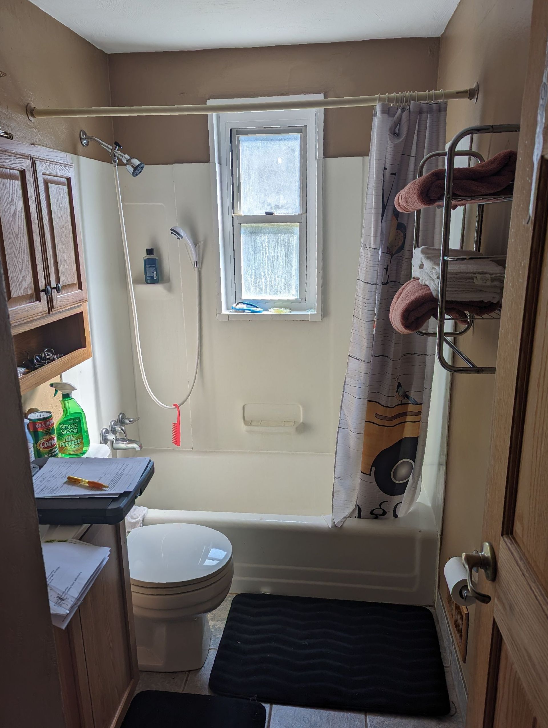 A bathroom with a toilet , tub , shower and window.