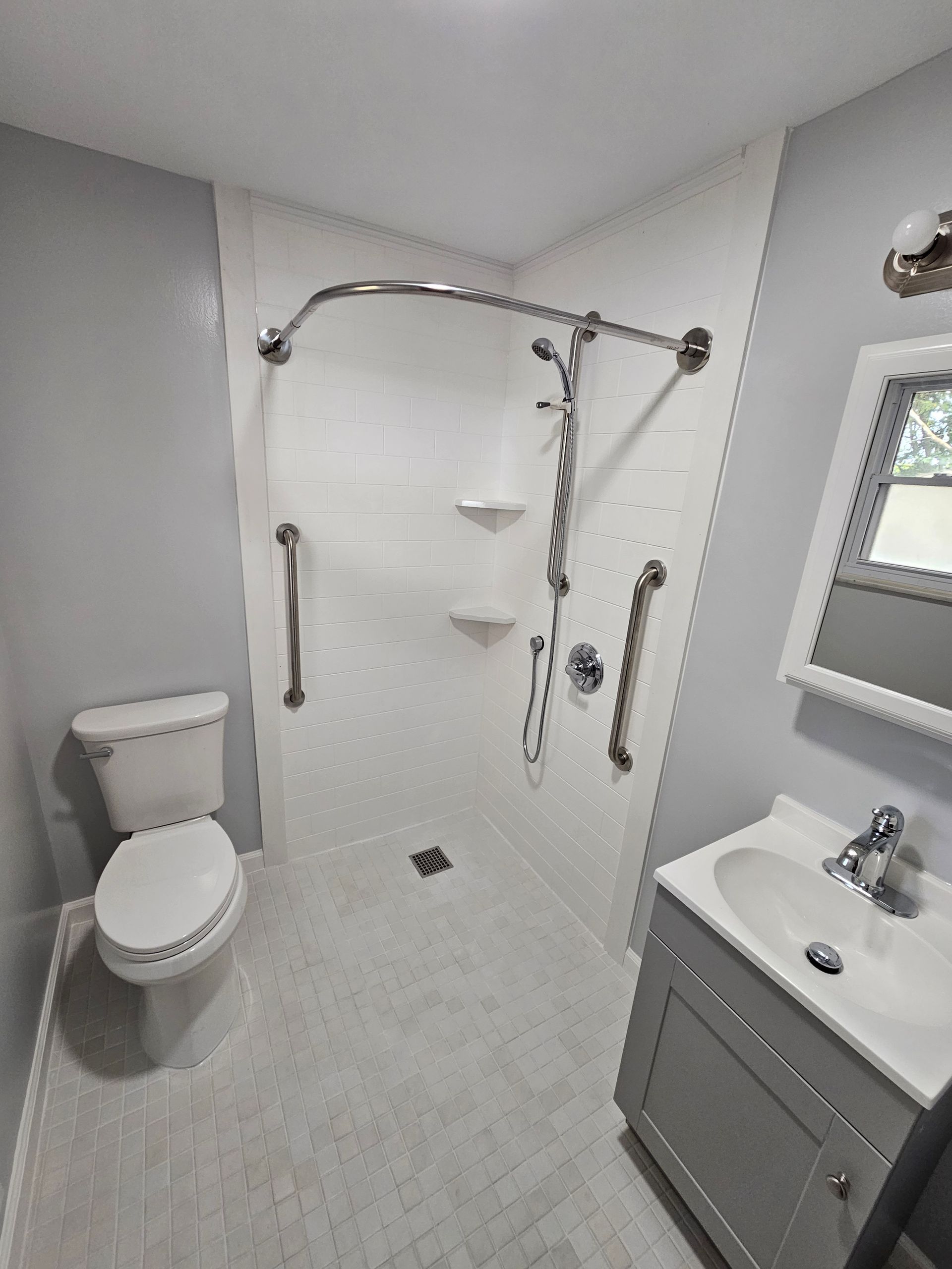 A bathroom with a toilet , sink , shower and mirror.