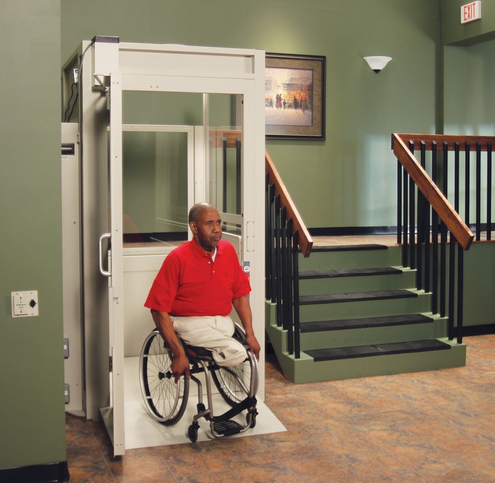 A man in a wheelchair is getting out of a Bruno Vertical Platform wheelchair lift by Altamria Ltd.