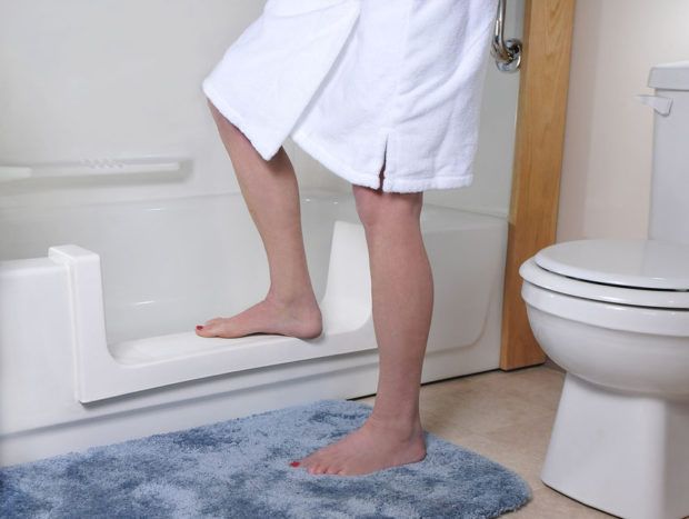 A woman in a white robe is standing next to a toilet in a bathroom