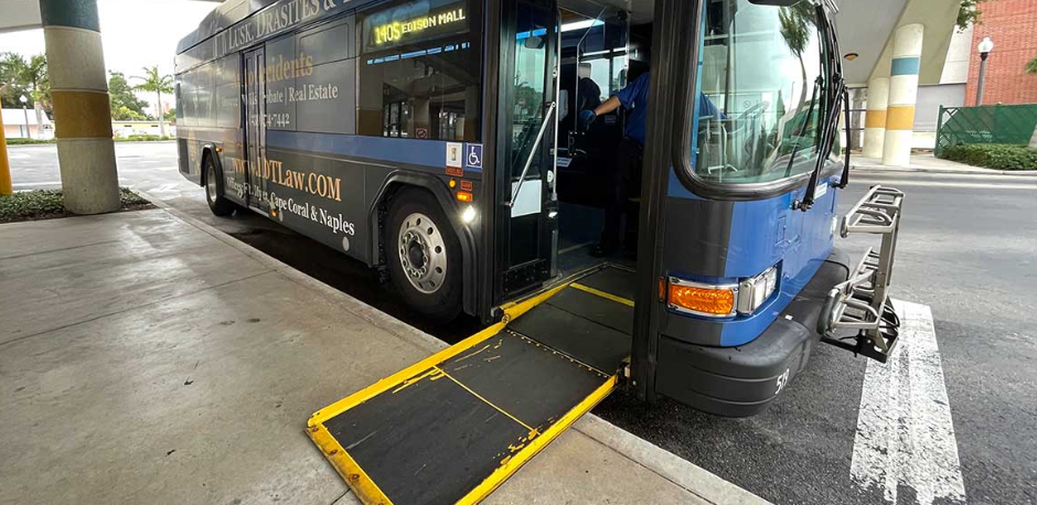 Blue bus with ramp extended, at a bus stop.