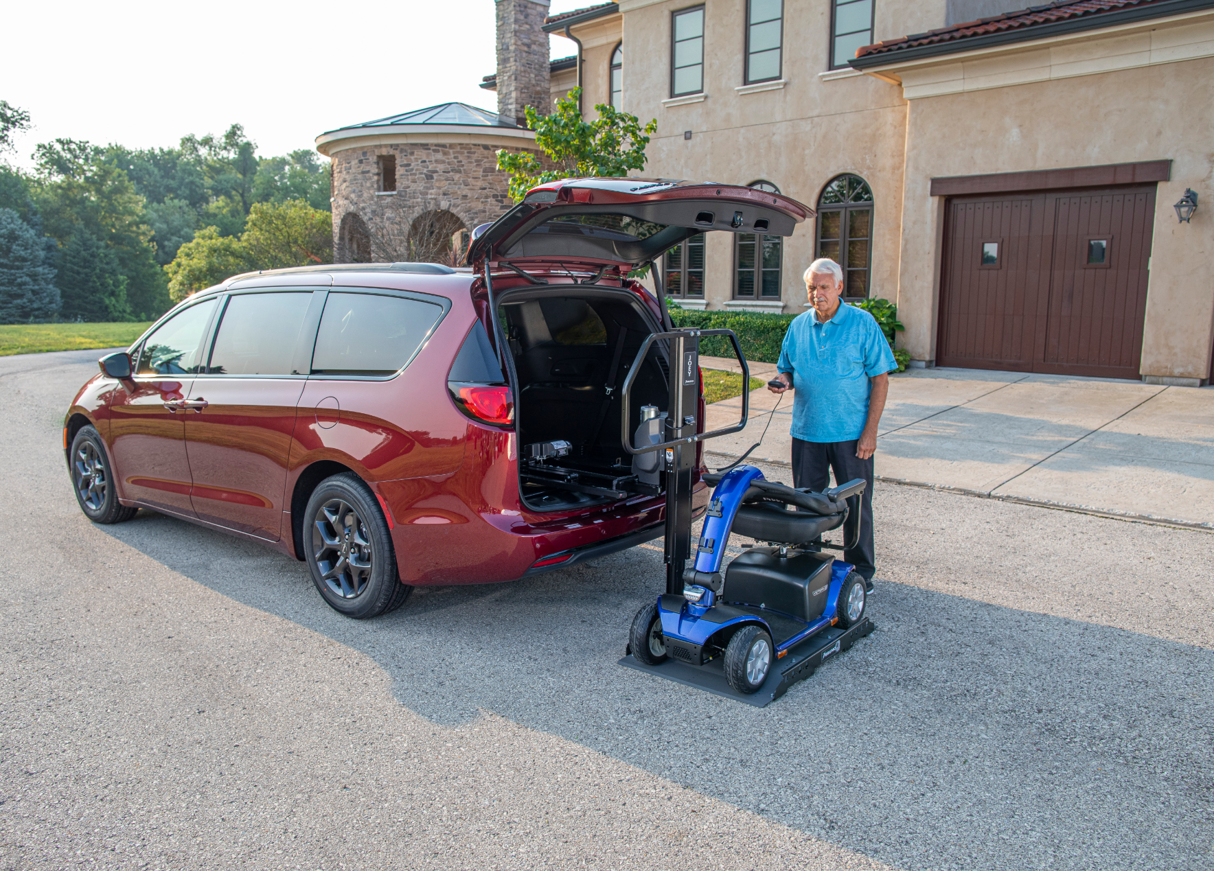 A man is loading a mobility scooter into the back of a van.